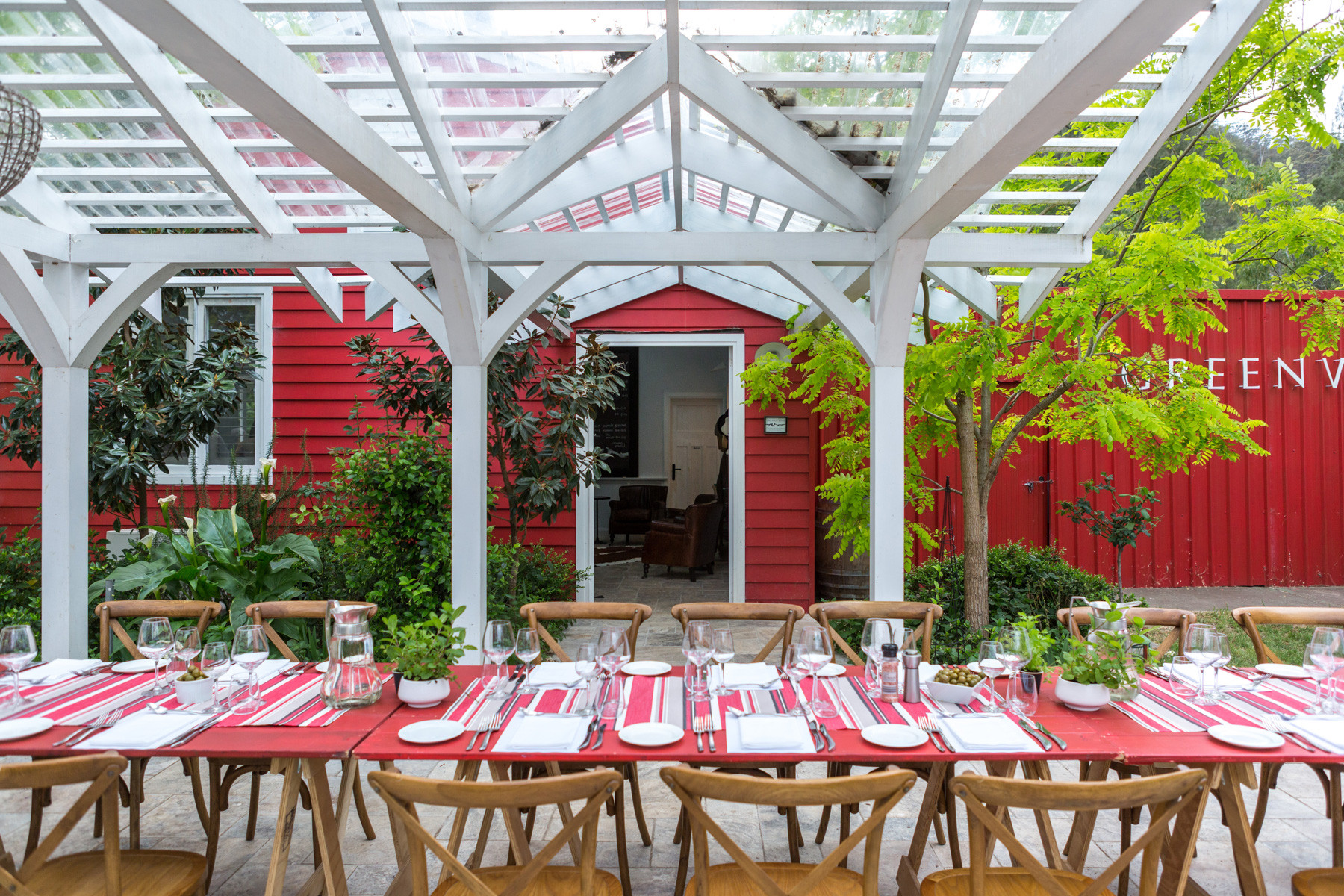 Red painted trestle tables in a line with wooden chairs on either side.
