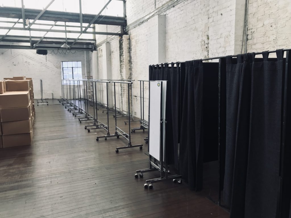 Boxes, clothing racks, mirrors and change room in large brick venue